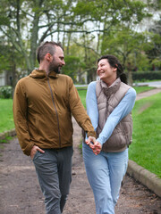 Obraz premium Happy middle-aged couple walking together outdoors in spring or autumn, enjoying nature and spending time hiking or exploring the park.