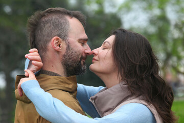 Middle-aged couple bonding outdoors in a park during a cool spring or autumn day, expressing warmth and affection in natural light.
