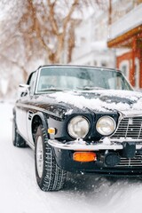 Fototapeta premium Snow-covered convertible parked under heavy snowfall, showcasing a classic car's elegance amidst winter scenery, creating a serene and picturesque atmosphere