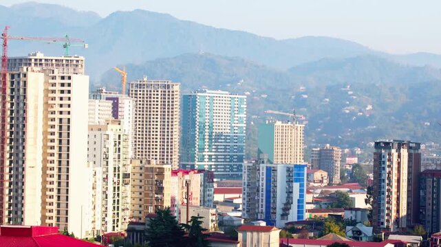 A city skyline with a mountain range in the background. The buildings are tall and the city appears to be bustling with activity