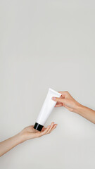 Female hand passing a tube of cream to another hand. Woman's hand hold cream tube. Cosmetic product branding mockup. Daily skincare routine. Cosmetic product mock up, template, close up, vertical
