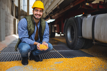 Young worker holding corn kernels during unloading