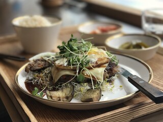 야채와 치즈를 얹은 햄버그스테이크와 반찬과 밥이 있는 쟁반