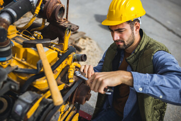 Young mechanic repairing truck and excavator engines