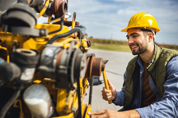 Young mechanic repairing truck and excavator engines