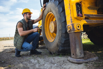 Excavator operator fixing tire on construction site