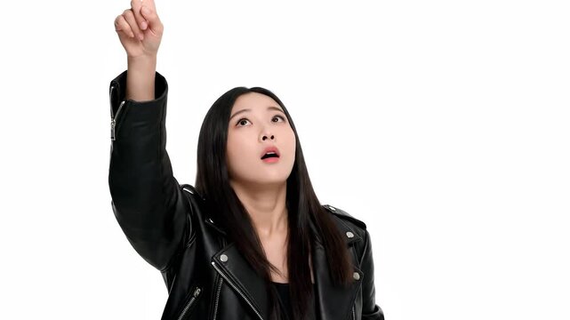 The woman in a leather jacket raises her finger confidently. Wearing a black leather jacket, the woman gestures upwards, showing assertiveness through her black attire.