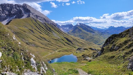 A picturesque alpine lake Monzabonsee surrounded by high mountains, against the background of blue sky with white clouds. Rufikopf, Tirol, Austria.