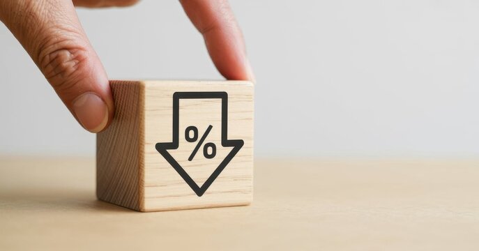 Market Decrease: A hand carefully places a wooden block displaying a downward arrow with a percentage symbol, indicating a financial decrease or drop in value.
