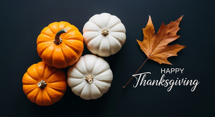 Happy thanksgiving arrangement of pumpkins and a fall leaf on a dark background