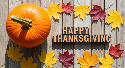 A vibrant pumpkin and colorful autumn leaves arranged around the words happy thanksgiving on a weathered wooden surface