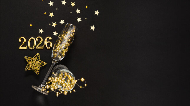Elegant New Year's composition with champagne glasses, gold ornaments and the numbers 2026 on a black background. Festive mood, a symbol of the New Year and a glamorous celebration.