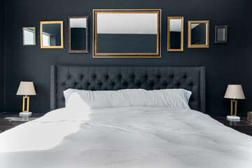 Luxurious bedroom with bed tufted headboard, mirrors, and gold lamps