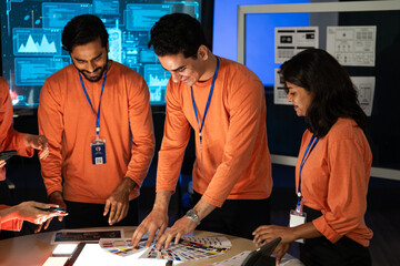 Smiling, diverse team of tech professionals reviewing a color palette and digital data on a table. Collaborating on branding and design in data center. creative teamwork and user interface development