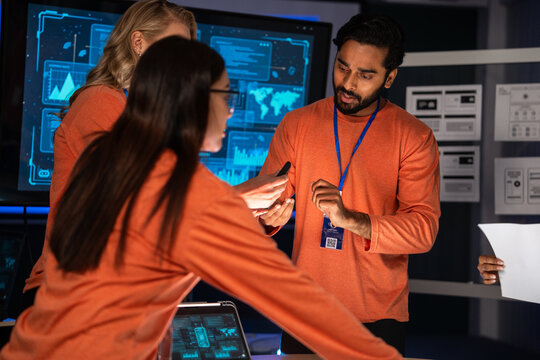 A diverse technology team is collaborating data analysis in a control room. Digital security and problem-solving with advanced tech for mission-critical operations. Project meeting and brainstorming