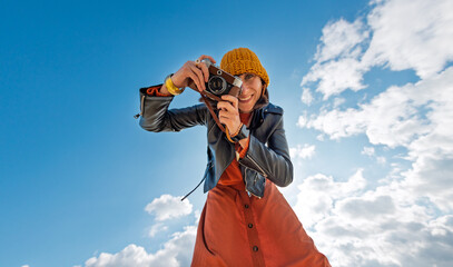 Woman taking photos outdoors. Young beautiful girl taking photos on camera while walking on the beach enjoying her weekend. close up.