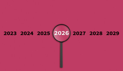 Lens, magnifying glass focusing on the year 2026 on a red background. Financial or stock market strategies and past and future events.
