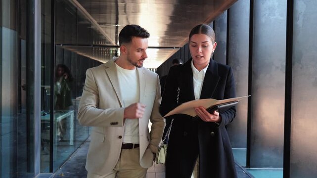 Two business professionals, a man and a woman, are engaged in a focused discussion while reviewing essential documents, showcasing their commitment to collaboration and effective communication in the