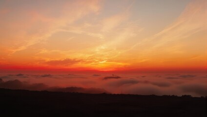Obraz premium A breathtaking sunrise over a sea of clouds, painting the sky with vibrant orange and red hues