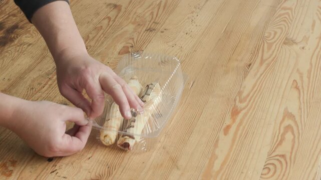 Hands Opening Plastic Clamshell Container with Crepe Dessert on Wooden Table, ASMR Sound.