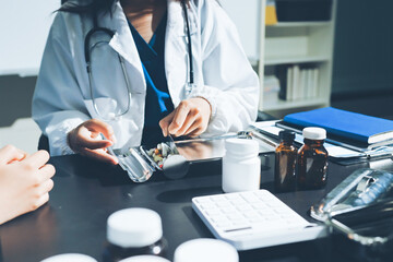 Female doctor holding a medicine bottle is checking the quality of medicine for any side effects the patient or not and recording patient information at the hospital. medical and health care concept