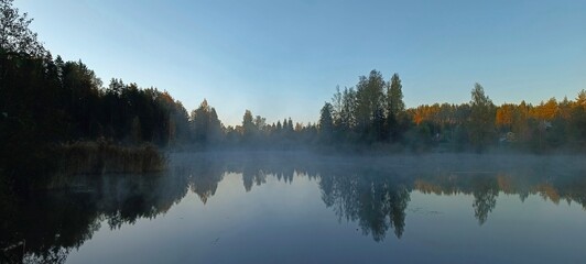 Panoramic view of the lake in the morning mist. Beautiful autumn landscape.