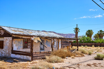 Abandoned Desert House With Faded Wood Porch Palm Trees And Distant Mountains