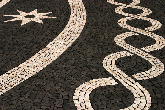 Portugal, Azores Islands, Ponta Delgada capital of Sao Miguel Island. Typical old Portuguese black and white mosaic cobblestone paving.  Volcanic basalt stone and limestone found on the island.