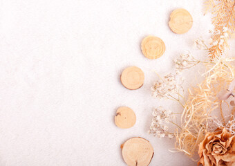 Top view boho natural composition with handmade decors on fluffy blanket texture. Round wooden slices, gypsophila, small white flowers, pine needles, natural raffia fiber, dried flower. Natural autumn