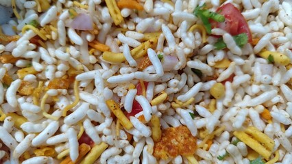 A closeup shot of Indian snack bhel puri with selective focus, showing puffed rice, sev, onions,...