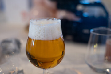 Cold beer in a glass with frothy head in a dimly lit pub