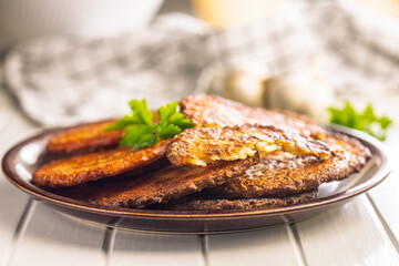 Fried potato pancakes on plate on white table.