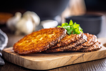 Fried potato pancake on cutting board on wooden table.
