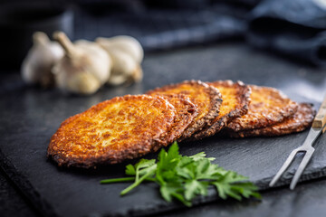 Fried potato pancake on black table.