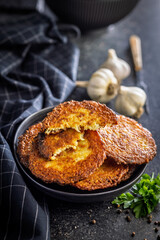 Fried potato pancake on plate on black table.