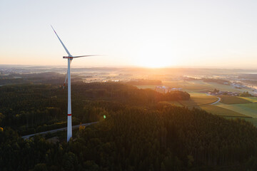 Wind Turbine at Sunrise Over Forest and Farmland