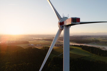 Wind Turbine at Sunrise Over Forest and Farmland