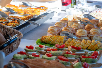 close up of breakfast buffet table in modern hotel in sunny morning with breads and cold and hot meats