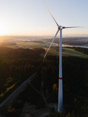 Wind Turbine at Sunrise Over Forest and Farmland