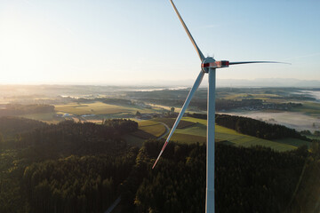 Wind Turbine at Sunrise Over Forest and Farmland