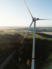 Wind Turbine at Sunrise Over Forest and Farmland