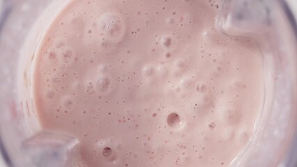 Strawberry and banana pink milkshake blended in blender with splashes. top view. slow motion. Healthy protein smoothie drink concept , food closeup