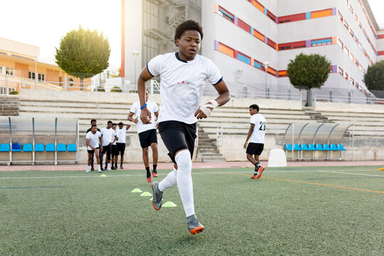 A group of young African boys are training on a soccer field.The athletes are practicing dribbling with cones on the ground. Concept of professional soccer players.