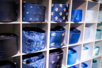 A vibrant wall display of rolled neckties arranged by color red, burgundy, blue, teal, green, brown...