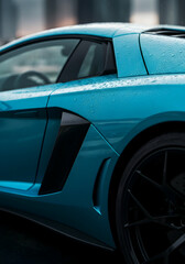 A close up of blue exotic car under neon city lights during rainy night