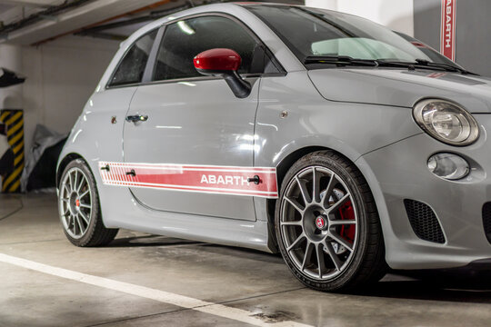 Detail of a red foil strip, during the installation of stickers on an Italian fast car Fiat 500 Abarth. Applying fast self-adhesive stripes.