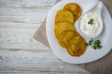 Potato pancakes with sour cream on a white plate. Rustic light style