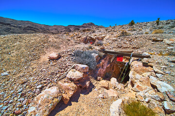 Abandoned Mine Entrance in Desert Landscape With Rocky Terrain and Distant Mountains