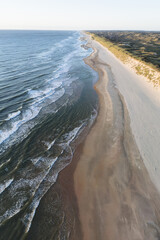 Aerial View of Serene Coastal Beach with Ocean Waves and Grassy Terrain