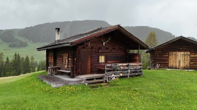 Drone flight near wooden cabin on green alpine meadow, Seiser Alm, Dolomites, Italy